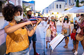 Street Afro musicians playing violin and wearing protective face mask, during COVID-19