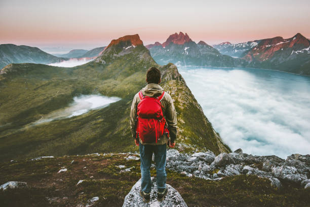 バックパックで夕日の山々を探索するハイカーの男 ノルウェーで一人でアクティブな夏休み屋外の旅を旅行ヒーシーライフスタイルアドベンチャーコンセプト - climbing men sea cliff ストックフォトと画像