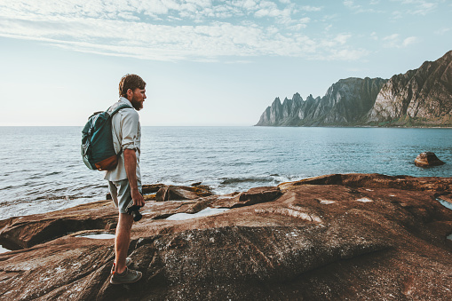 Man backpacker walking alone on beach traveling in Norway lifestyle summer vacations outdoor Okshornan peaks view