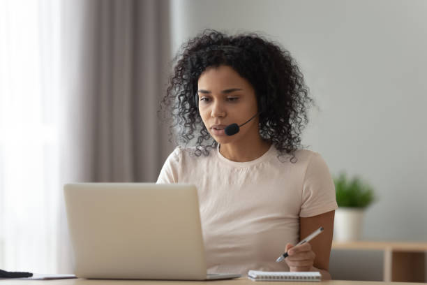 istock Focused African American woman in headset using laptop, writing notes 1264479330