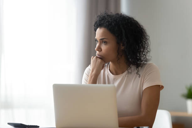 istock Thoughtful African American woman using laptop, pondering task 1264479347
