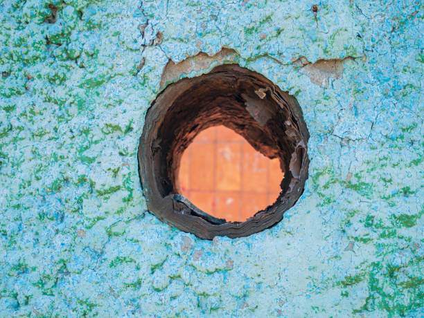 Old turquoise plaster wall texture with hole. Retro painted putty building background with copy space. Stylish blue surface, detailed stones backdrop. Wallpaper textured screensaver front view design.