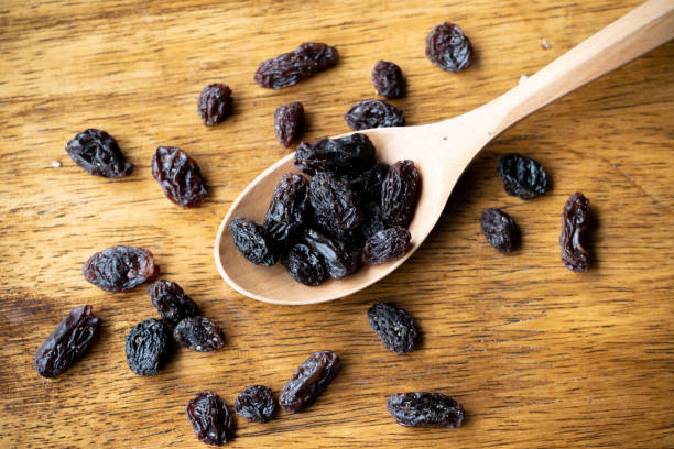 istock dried raisins on wooden spoon. Selective focus on some raisins. 1264482200