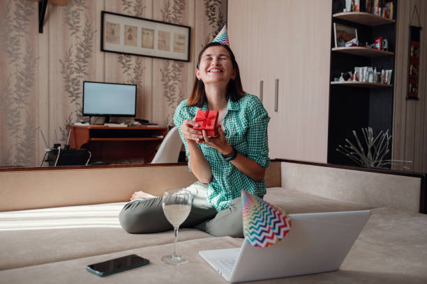 Girl celebrating birthday online in quarantine time. Girl celebrating birthday online in quarantine time through video call virtual party. Coronavirus outbreak 2020. Woman opening a gift and have positive emotions. virtual birthday celebration stock pictures, royalty-free photos & images