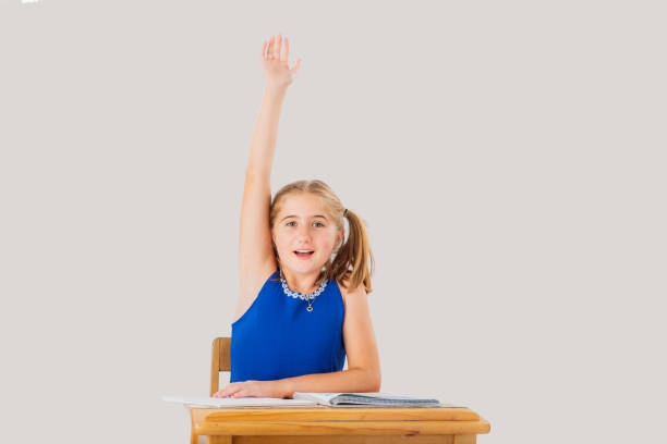 istock A nine year old student has a hand raised to ask or to answer a question while seating at her school desk. 1264484902