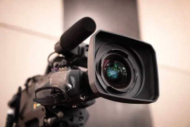 Photo of Television camera lens, Film of Video movie recording films shooting of grand opening in conference hall Live streming for presentation with bokeh light background. Media Production Concept