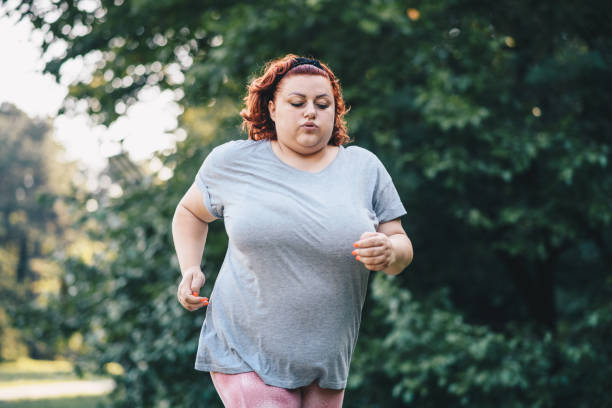 zbliżenie obrazu otyłej kobiety biegającego na łęcznie na bieżni, wykonującego trening odchudzania - running jogging treadmill weight training zdjęcia i obrazy z banku zdjęć