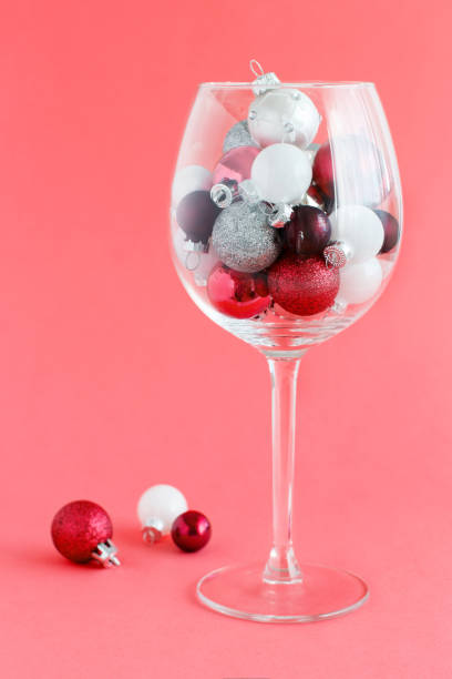 istock Christmas baubles in a wine glass on a light red background 1264492448