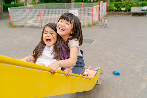 Two sisters are happily enjoying their time together in a public park.