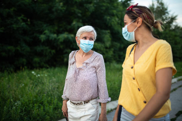 istock Mother and daughter with protective face mask, walking down street and talking 1264500902