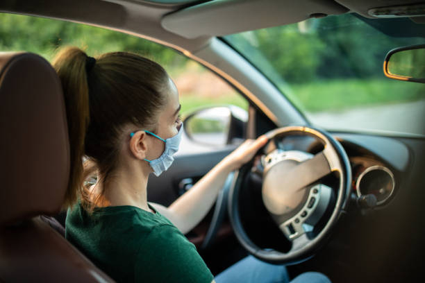 istock Woman with protective face mask driving car 1264500940