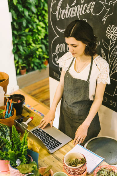 istock Flower shop worker checking emails from a laptop 1264508231