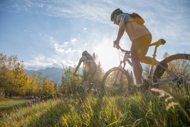 mountainbiker fährt im herbst auf grasweg - recreational pursuit mountain biking nature outdoors stock-fotos und bilder