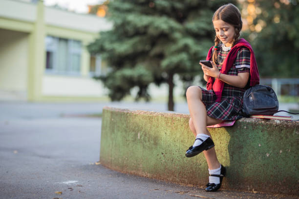istock School girl sitting on the wall and text messaging 1264519543