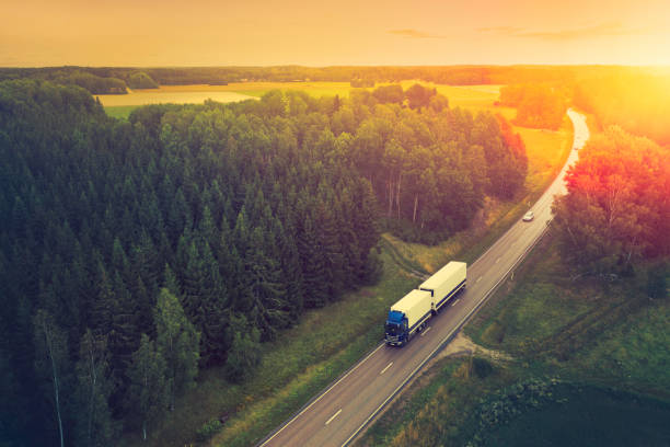 Aerial view of a truck travelling down a highway in a forest landscape in the Södermanland region of Sweden.
