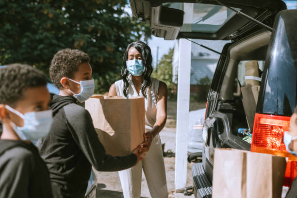 istock Family Unloading Groceries From Car With Face Masks 1264525677
