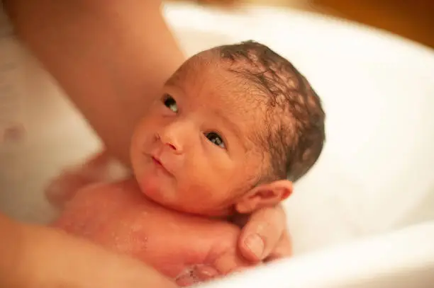 Photo of newborn baby girl having a bath by her mother.