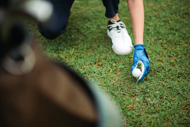 Crop shot of asian chinese golfer wear blue glove putting golf ball on a tee at the golf course selective focus, getting ready before tee off golf concentration stock pictures, royalty-free photos & images