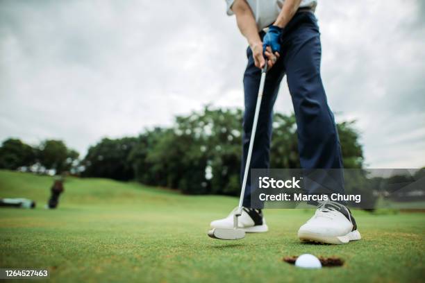 Crop Shot Of Asian Chinese Young Male Golfer Tapping The Golf Ball Into A Hole At Golf Course Stock Photo - Download Image Now