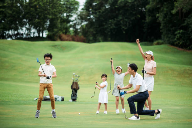 アジアの中国の笑顔の家族ゴルファーは、彼らの息子がゴルフコースで最初のボールをタップした後に幸せと興奮 - golfer competitive sport golf recreational pursuit ストックフォトと画像