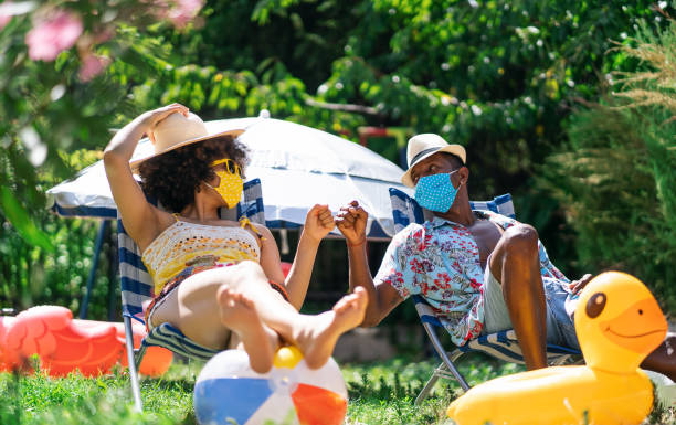 Afro Couple wearing protective face mask having staycation fun on back yard and practicing alternative greeting, during COVID-19 Afro Couple wearing protective face mask having staycation fun on back yard and practicing alternative greeting, during COVID-19 staycation photos stock pictures, royalty-free photos & images
