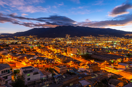 The skyline of Quito at sunset with night lights with the Pichincha volcano, Ecuador.