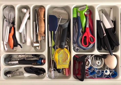 Top view of a kitchen drawer full of random cooking utensils