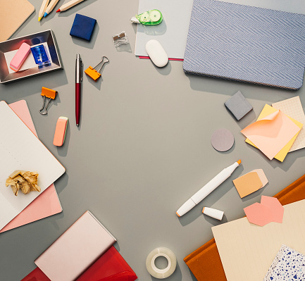 Office/school supplies: a flat lay composition including pens, pencils, notebooks, and other work/study-related objects, including technology.