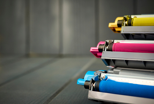 Set of rollers in color laser printer ink cartridges on wooden background