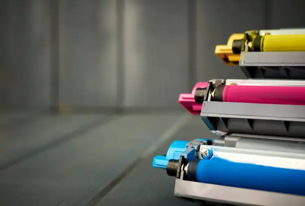 Photo of Set of rollers in color laser printer ink cartridges on wooden background