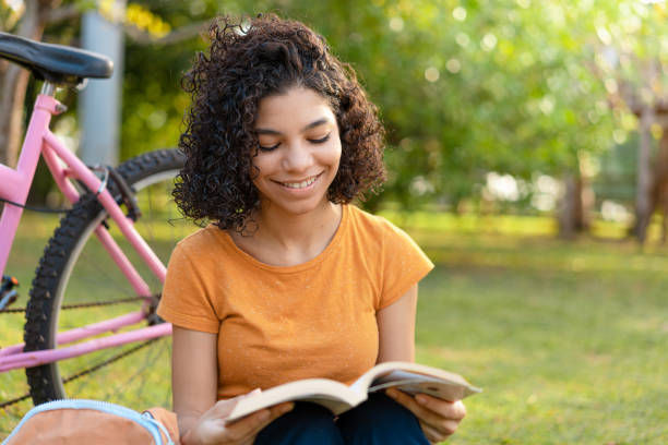 adolescente chica leyendo libro en el parque - childrens literature fotografías e imágenes de stock