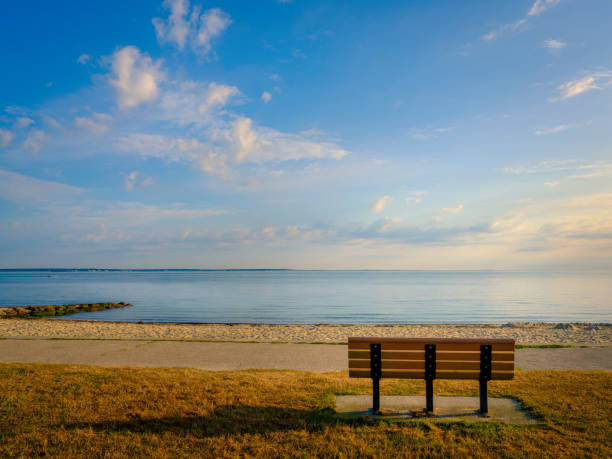 tranquil seascape and dramatic cloudscape over the bench on cape cod beach - beach bench cape cod sunset imagens e fotografias de stock