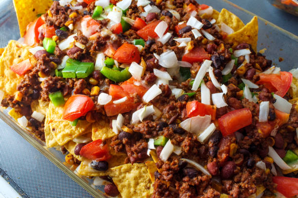 Loaded Chili Beef Nachos Beef chili nachos loaded with toppings like tomatoes green bell peppers and onions nacho chip photos stock pictures, royalty-free photos & images