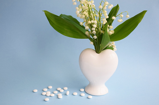 Lily of the valley flowers in blue vase and gift box against rustic wall. Greeting card for woman day.