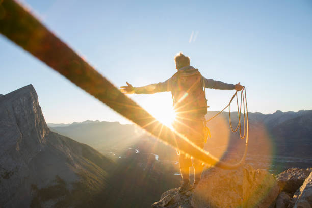 альпинист разводит оружие, чтобы отпраздновать на вершине горы - climbing achievement leadership adventure стоковые фото и изображения