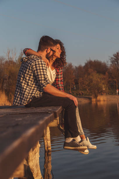 istock Couple sitting at lake docks 1264539080