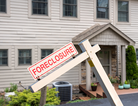 Mockup of a foreclosure sign in front of a modern townhome or townhouse to illustrate recession fears due to coronavirus