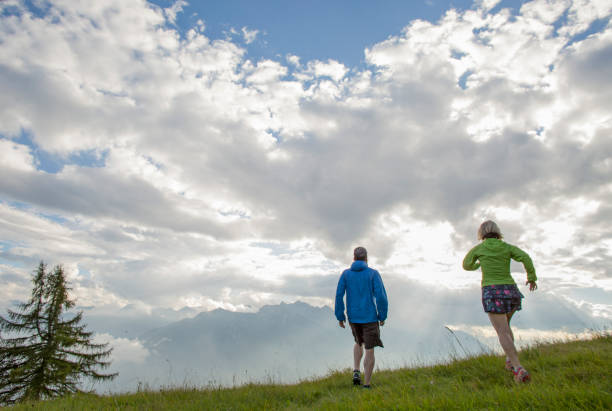 istock Trail runners ascend high mountain slope, through meadow 1264539222