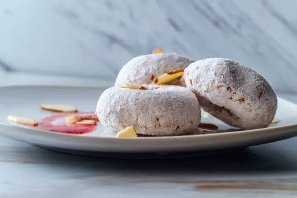 Powdered sugar cake doughnuts with holes served with raspberry jam and slivered almonds