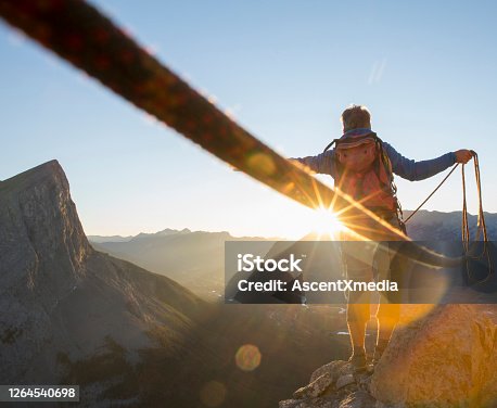 istock Mountaineer spreads arms to celebrate on mountain summit 1264540698