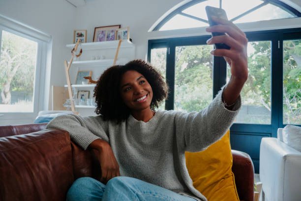 istock mixed-race woman taking selfie on the couch 1264540972