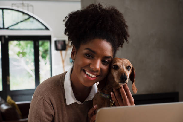 istock mixed race women playing with dog with laptop open 1264540998
