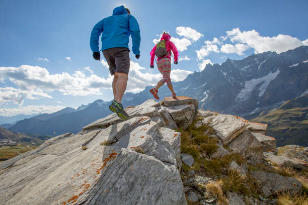 Trail runners ascend high mountain ridge Mountain range distant cropped pants photos stock pictures, royalty-free photos & images