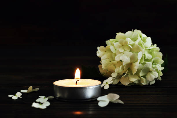 istock Funeral flowers and candle on dark background 1264542681