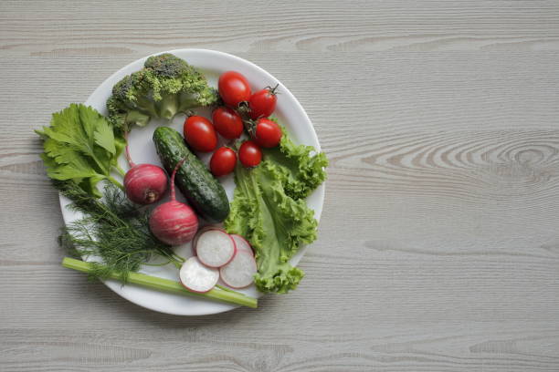 istock Fresh vegetables in a white plate on a light wooden table 1264544841