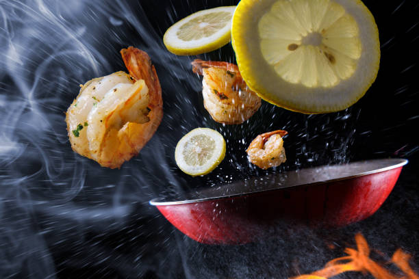 Tossing Cooking Lemon Shrimp Stir frying and tossing shrimp with sliced lemon concept with steam smoke and flames food state preparation shrimp prepared shrimp stock pictures, royalty-free photos & images