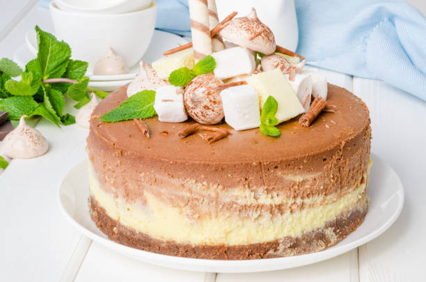 istock Marble chocolate coffee cheesecake with meringue, marshmallow and chocolate on top on white wooden background. 1264548154