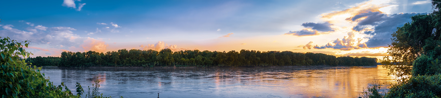 Beautiful panorama of Missouri River at sunset in summer; woods in background