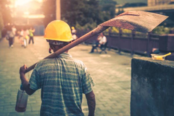 Chinese worker carrying his shovel on his arm and going home after finishing his work shift
