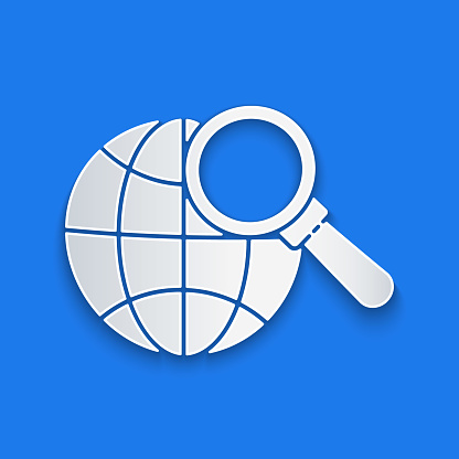 Paper cut Magnifying glass with globe icon isolated on blue background. Analyzing the world. Global search sign. Paper art style. Vector Illustration